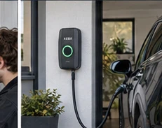 Wallbox mit angeschlossenem Ladekabel neben einem geparkten Auto